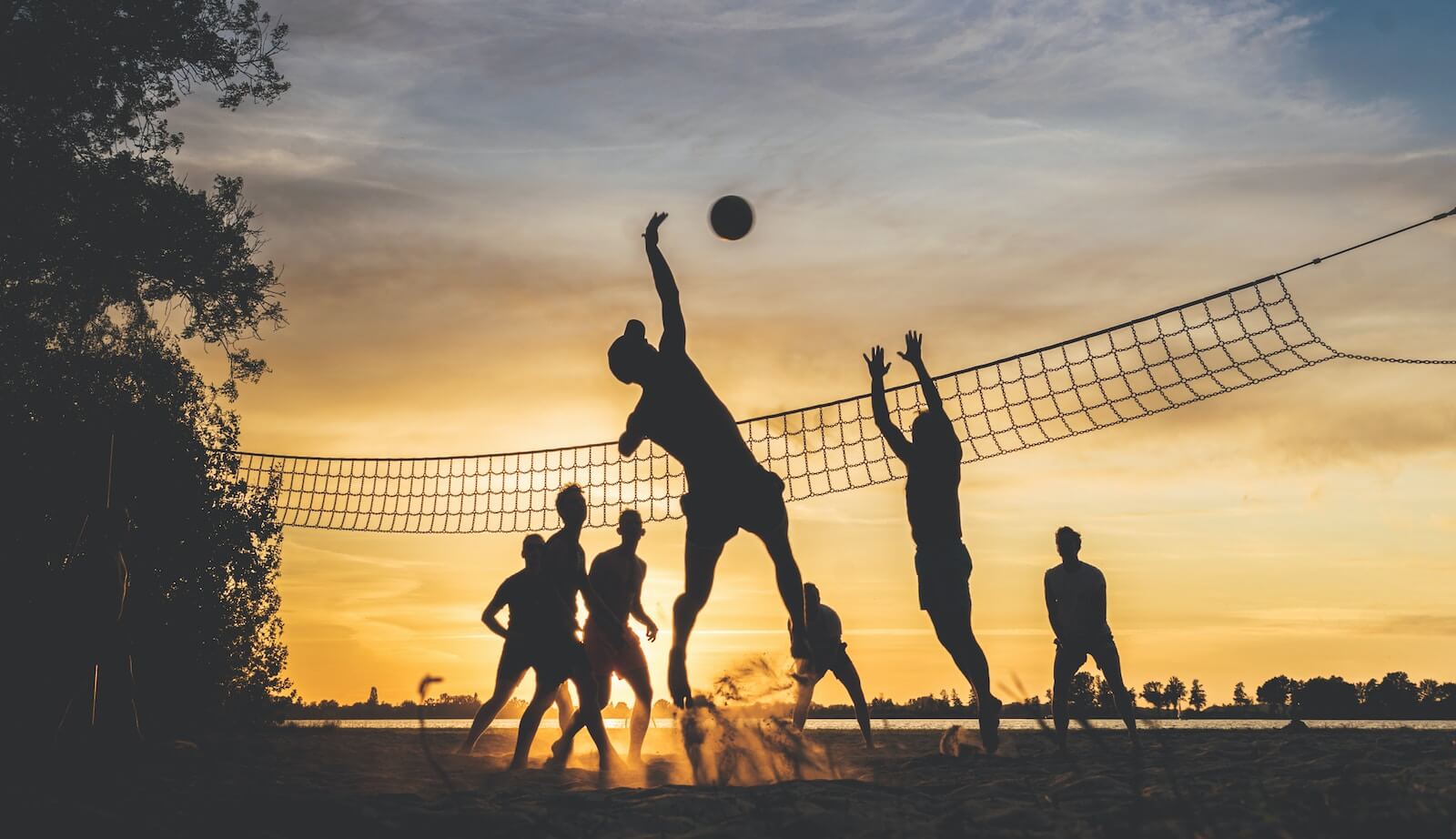 People playing volleyball at sunset