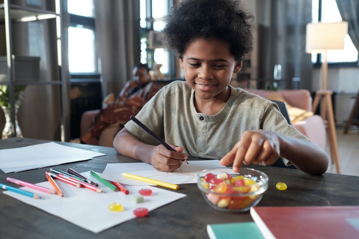 Child drawing and eating candy