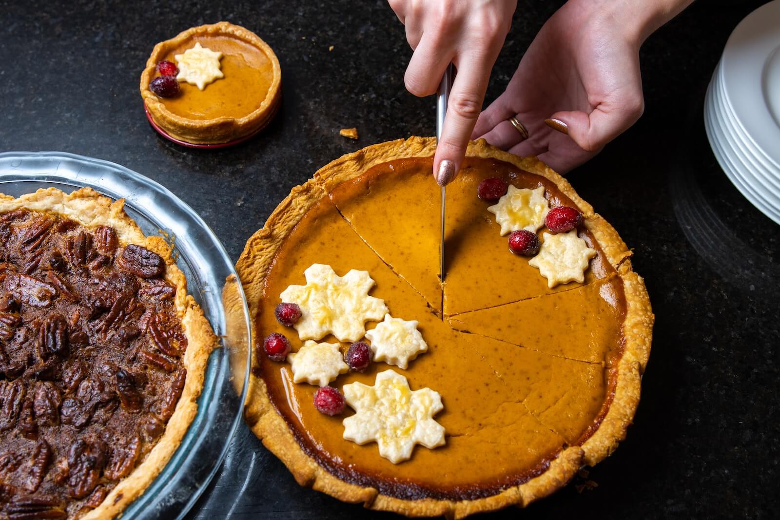 Someone cutting a pumpkin pie